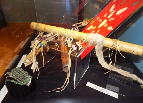 Display case with flutes, arrowheads,  and trade beads