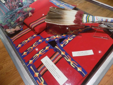 Display case of Osage items including ribbonwork and fan